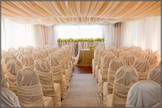 Sultans tent wedding decor with chair covers and ceiling drapes.