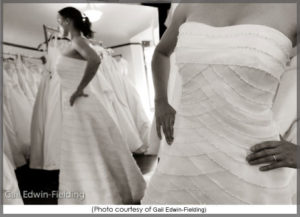 Bride trying on a wedding dress in front of a mirror.